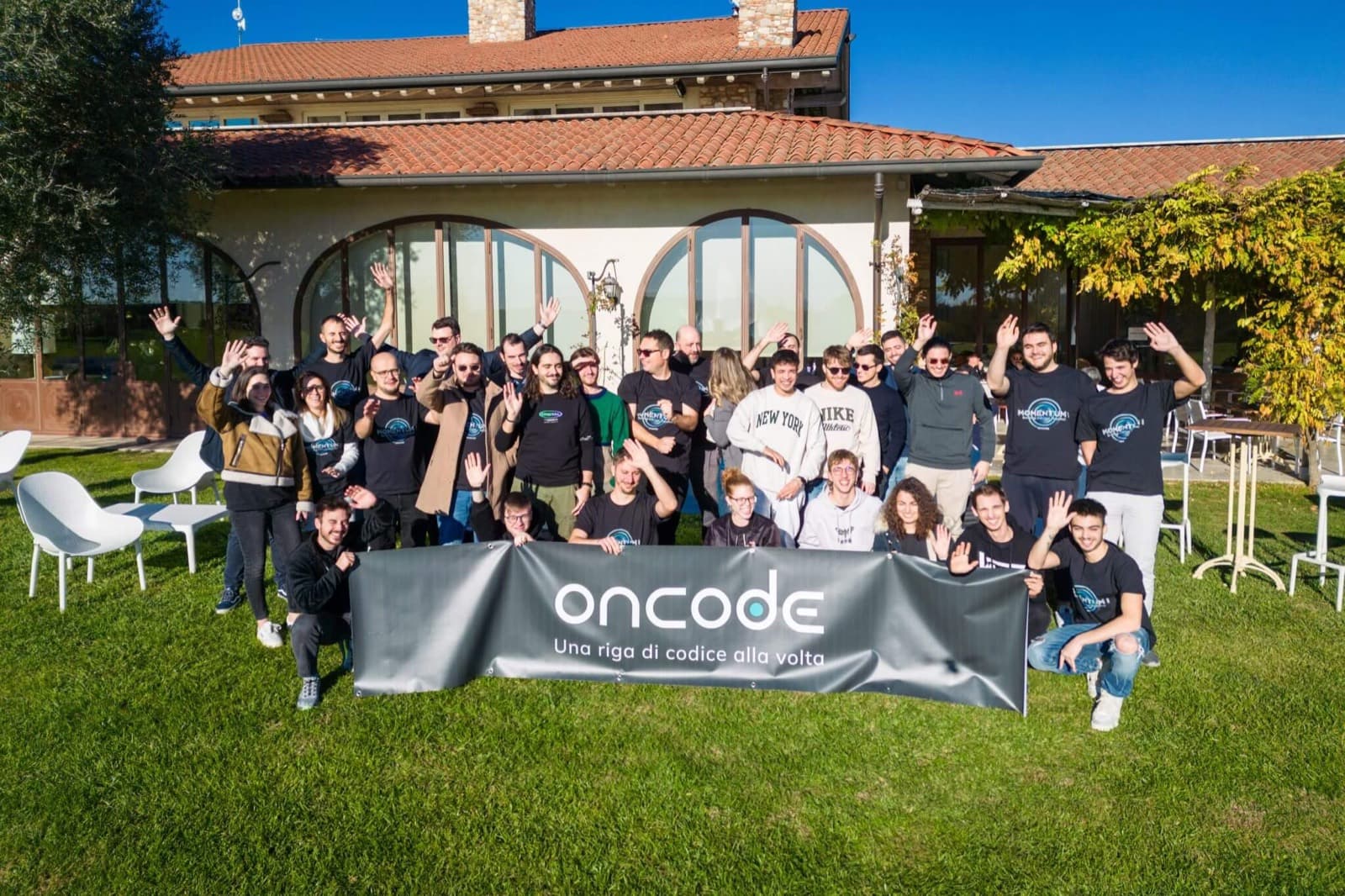 Il team Oncode al completo, all'aperto davanti alla sede, dietro lo striscione «Una riga di codice alla volta»